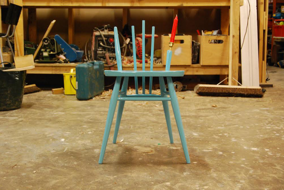 A blue, wooden chair, missing part of its back.