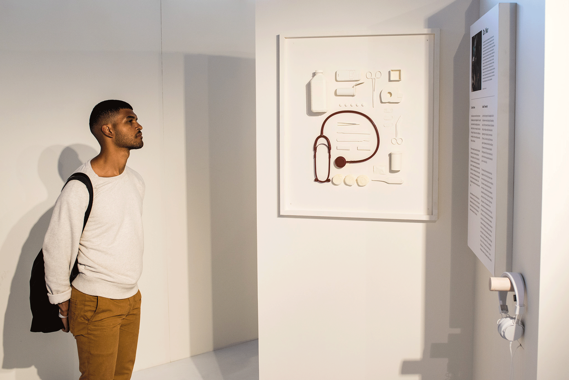 A young man reading display text in a white room.