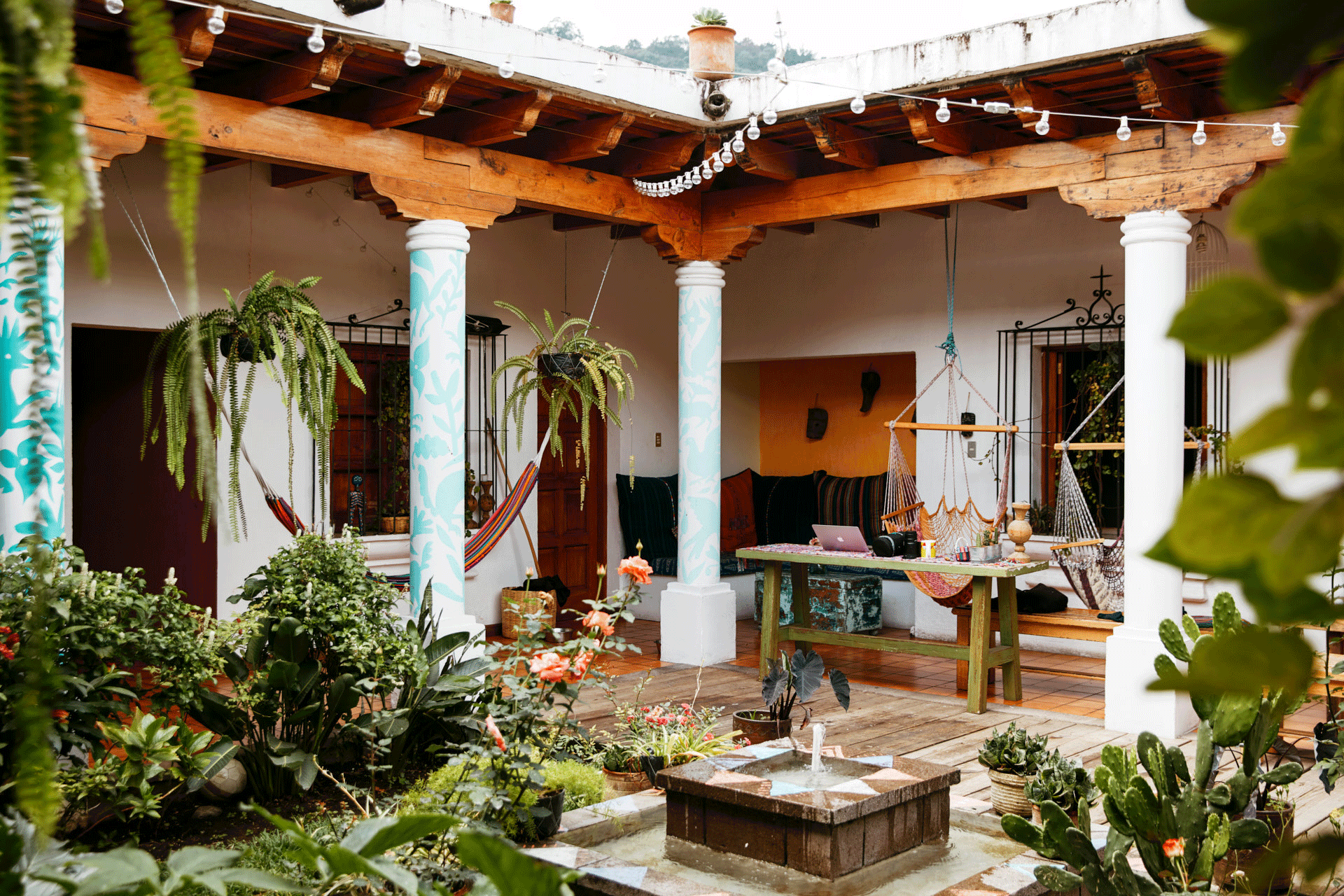 An open courtyard with a fountain, hammock chairs, and twinkle lights strung overhead.