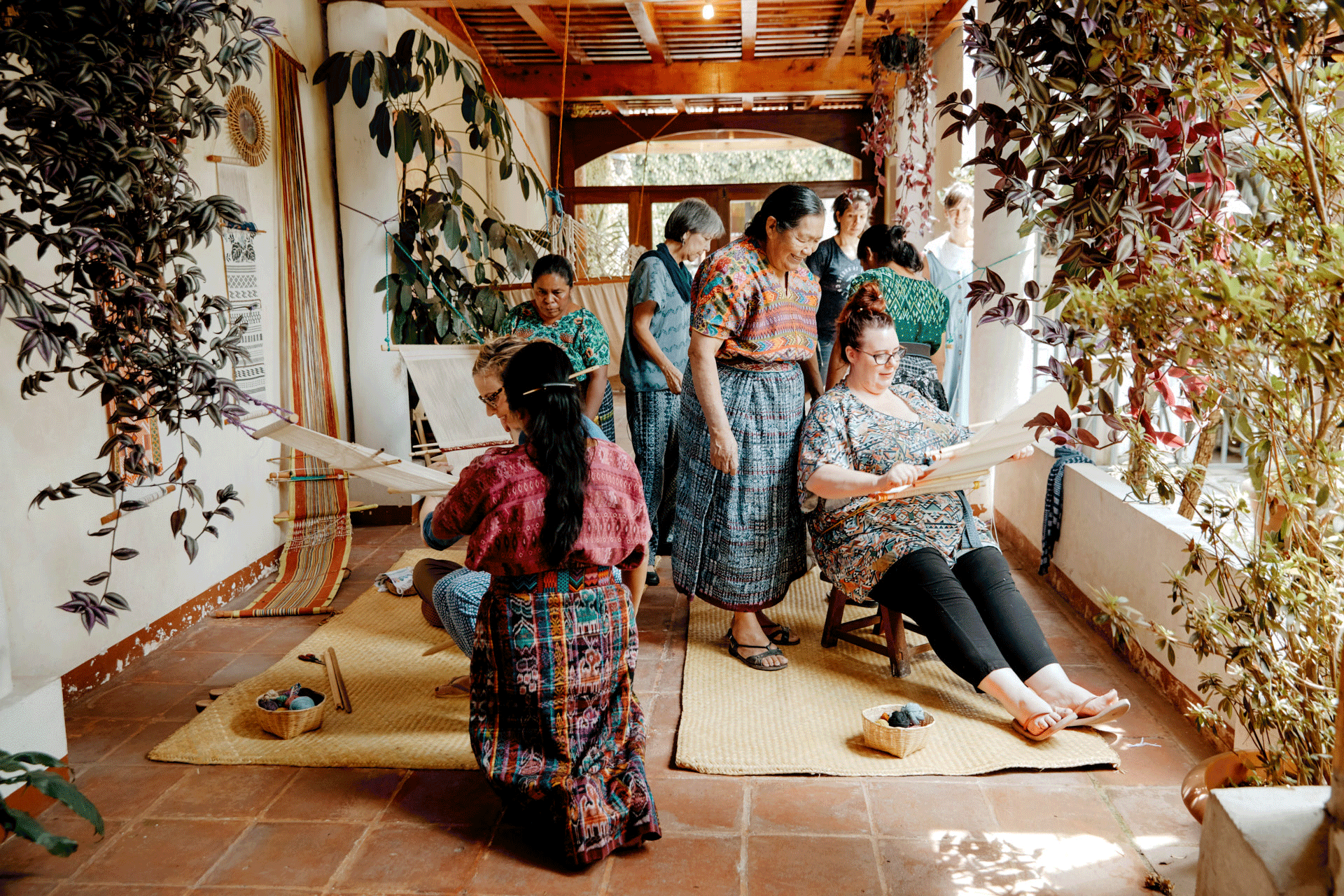 Multigenerational women gathered in a courtyard weaving.